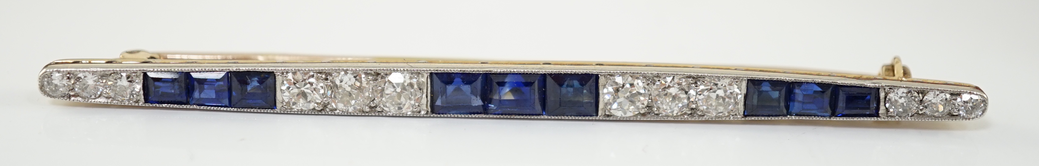 An Art Deco, round cut diamond and rectangular cut sapphire cluster bar brooch